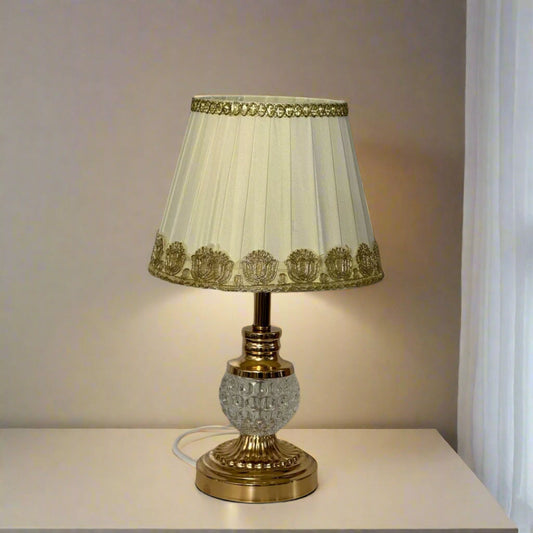 Ornate gold and cream table lamp with decorative gold lace trim on the fabric lampshade.